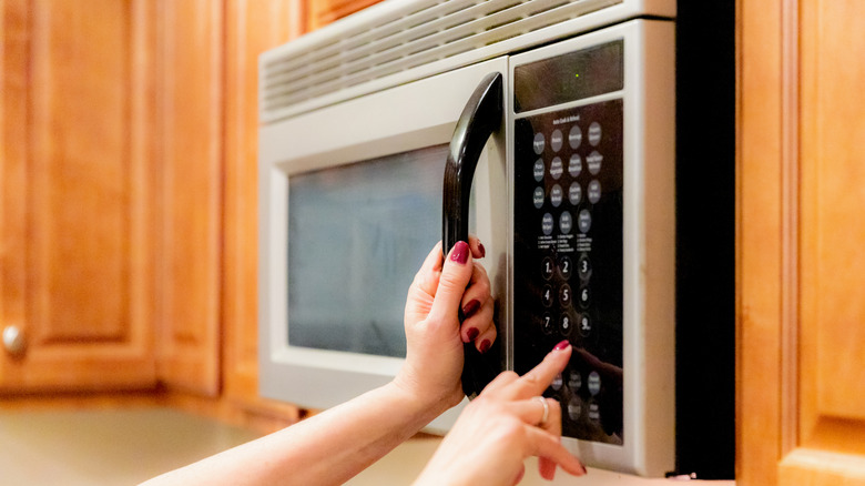 person using a microwave in a kitchen