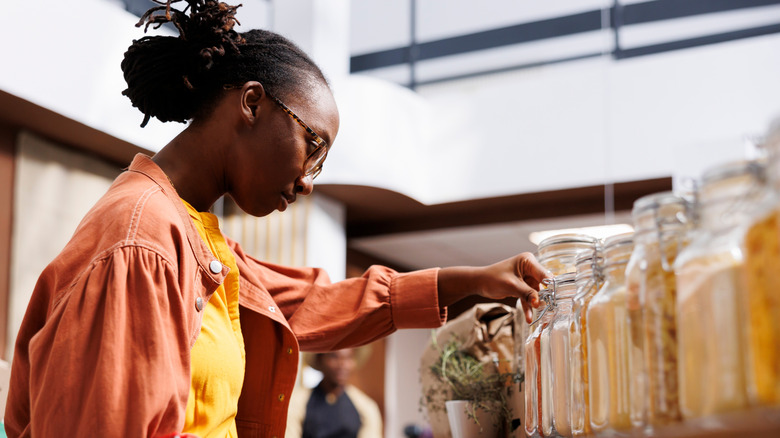 A young woman inspects a row of glass jars