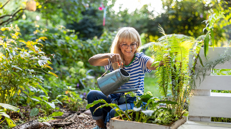 A woman tending to a large overgrown green garden