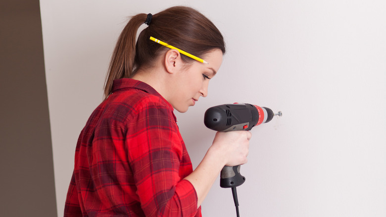 woman drilling into wall