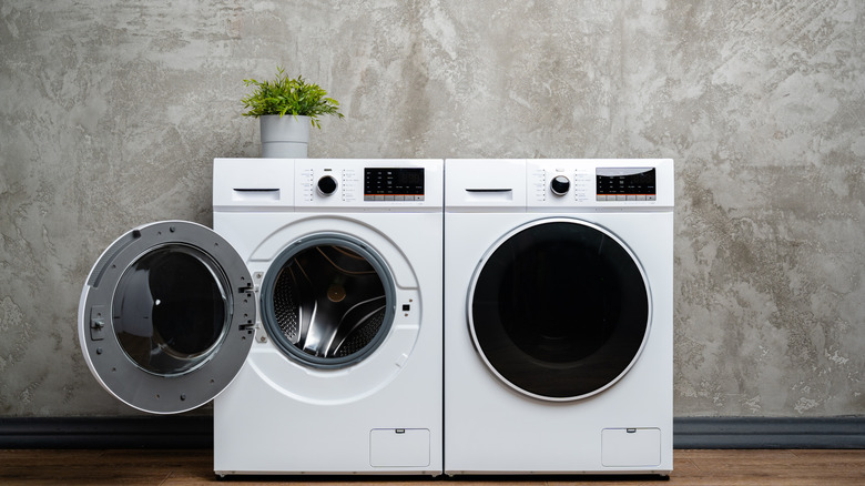 white laundry machines and a concrete wall