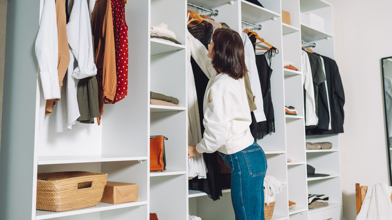 lady reaching into a full closet