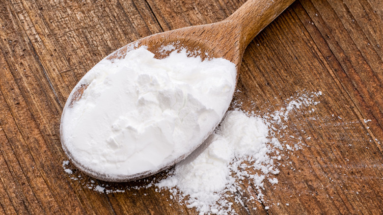 A spoon full of cornflour on a wooden table