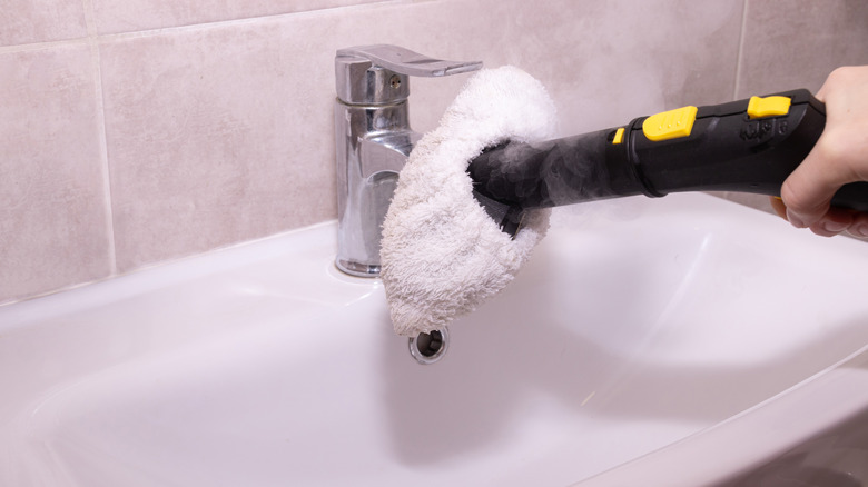 person steam cleaning faucet