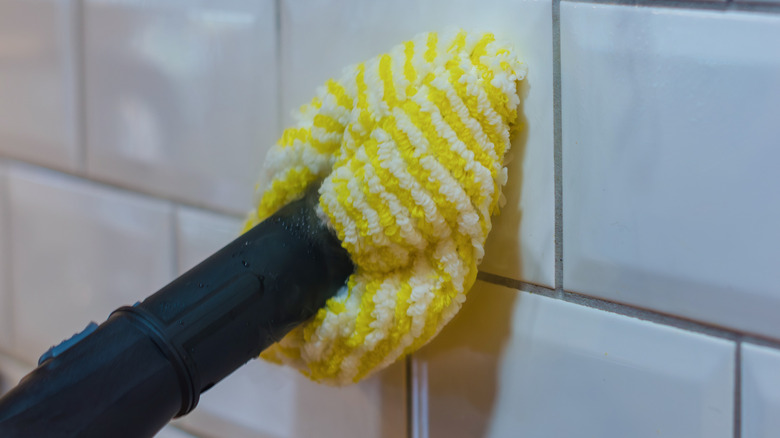 closeup of person steam cleaning tile wall