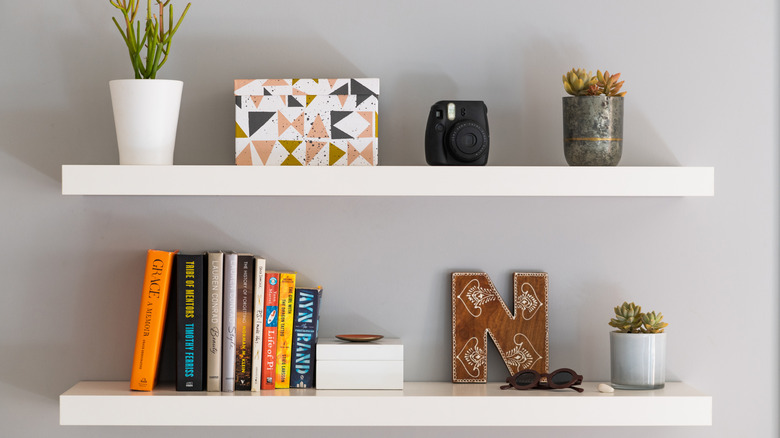 Two floating shelves mounted on a wall holding various items