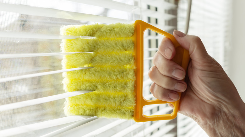 A hand dusting window blinds