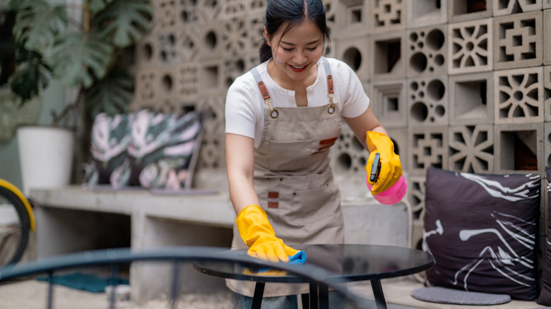 person cleaning patio furniture with spray bottle and cloth