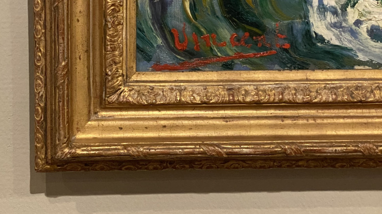 The artist Vincent van Gogh's signature in the corner of a framed oil painting on the wall of a museum.