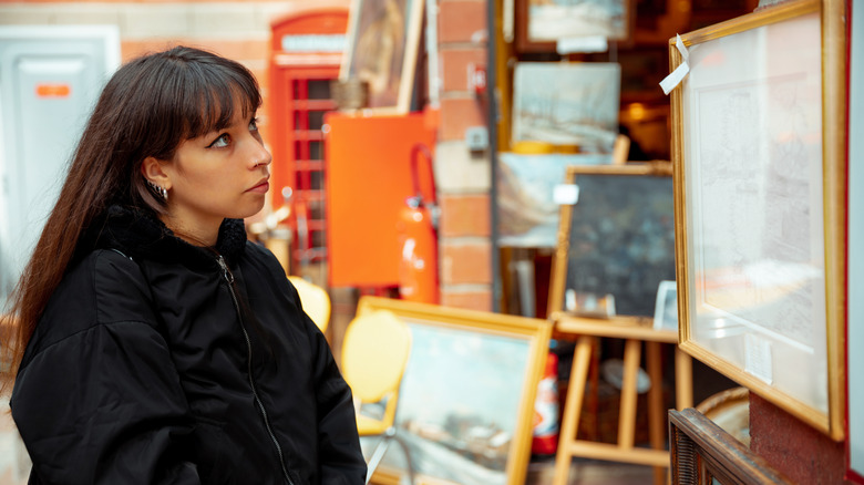 A person looking at paintings for sale