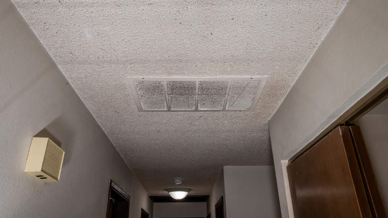 A hallway popcorn ceiling with an air vent installed.