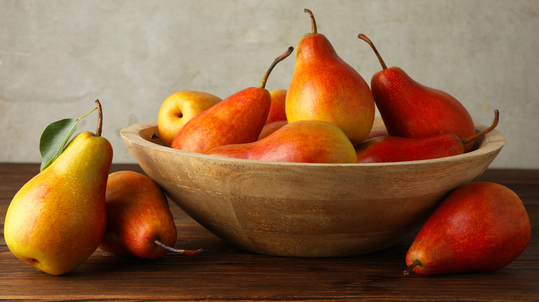 Pears ripening in a wooden bowl on a kitchen counter or tabletop.