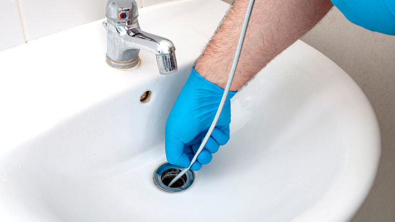 Person using drain snake sink