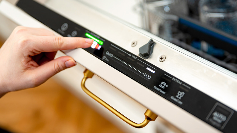 woman pushing eco mode button on dishwasher