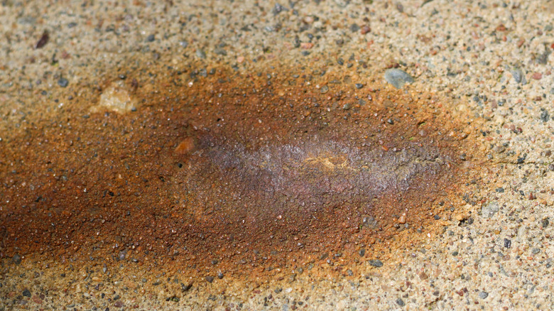 A close-up image of a rust stain on a concrete sidewalk