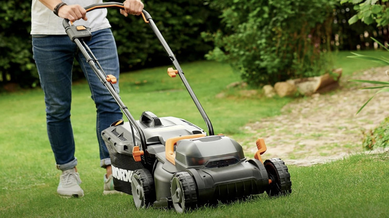 A person mows the lawn with the WORX cordless electric lawn mower