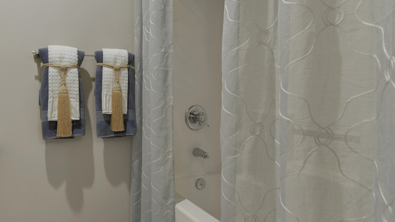 sleek modern bathroom with sheer shower curtain and black bathroom fixtures in a sleek white and black color palette