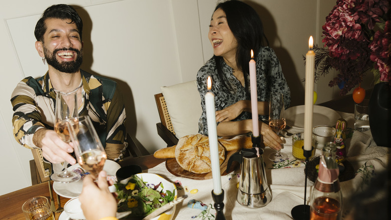 People gathered around a stylish dining table, smiling, and raising a glass