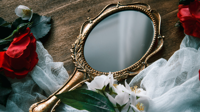 Rusty silver hand mirror on a wooden surface