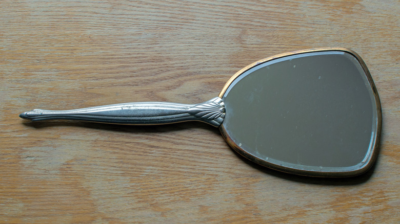 Antique hand mirror on a wooden surface