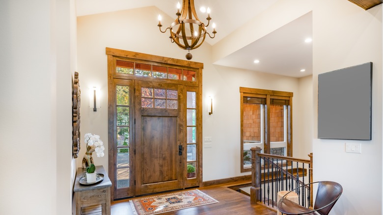 Cozy entryway with wood doors and windows, a chandelier, and wall sconces