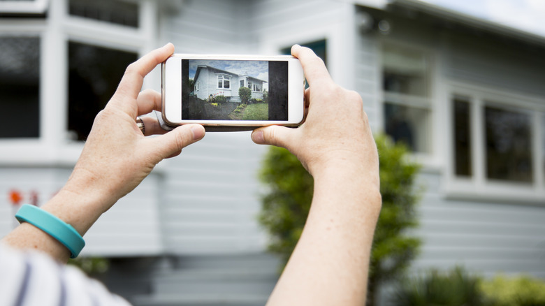 Person photographing home on their smartphone