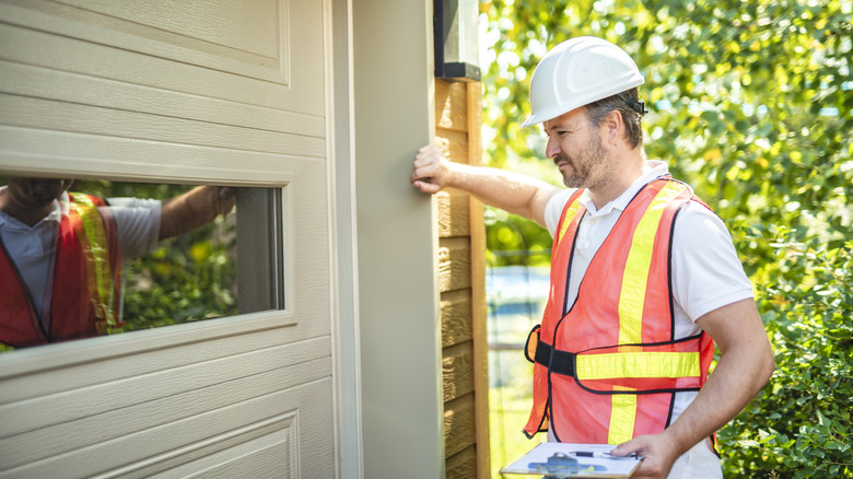 Man in orange hi-vis vest inspecting a garage door