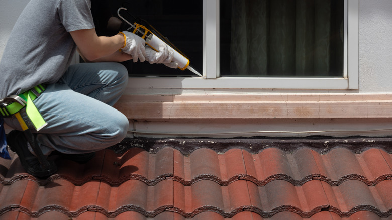 Person applying caulking around a window frame