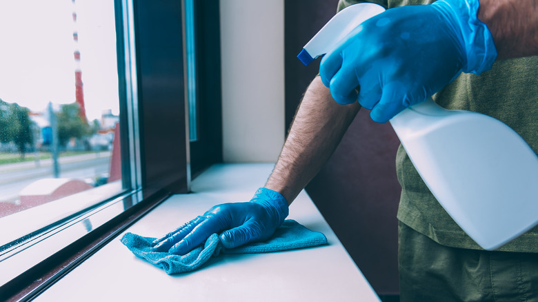 Spraying bleach on windowsill