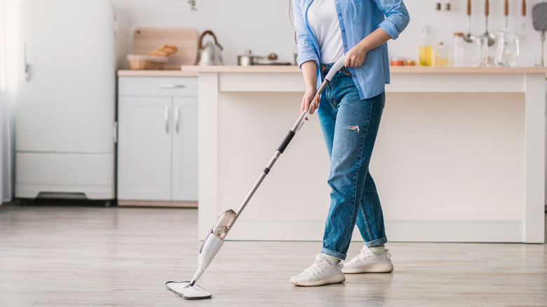 Woman dry mops kitchen floor