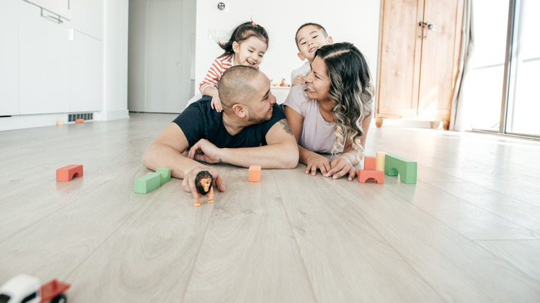 A family of four plays with toys on a luxury vinyl floor.