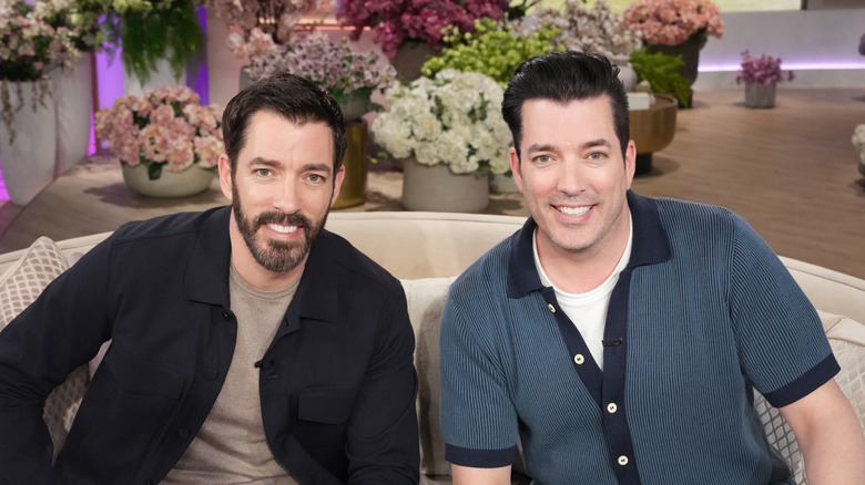 The Property Brothers sitting together on a sofa.