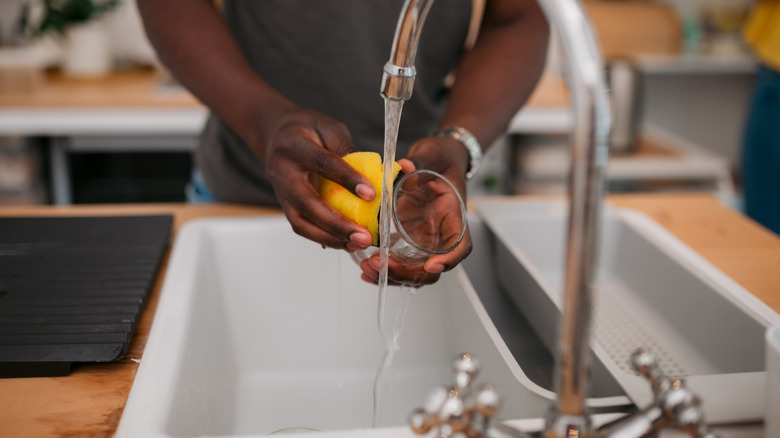 Man rinses glass with sponge