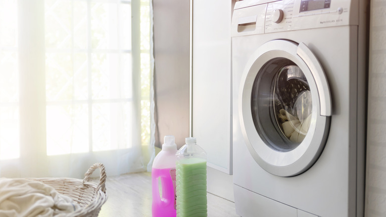 washing machine next to detergent and laundry
