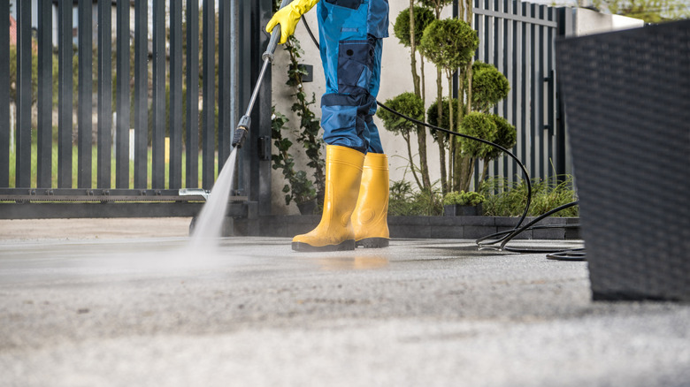 Someone pressure washing a concrete driveway.