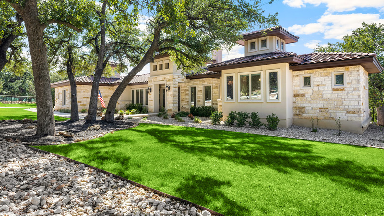 A house with nice curb appeal and some unidentifiable newly planted shrubs in the front garden.
