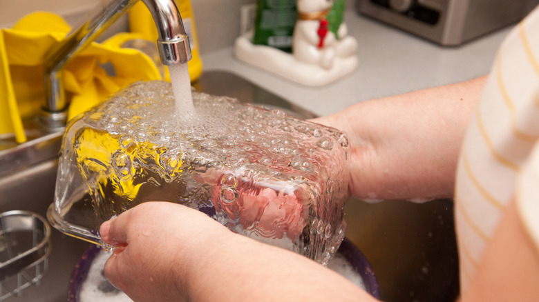 Woman washing glass Pyrex dish in kitchen sink