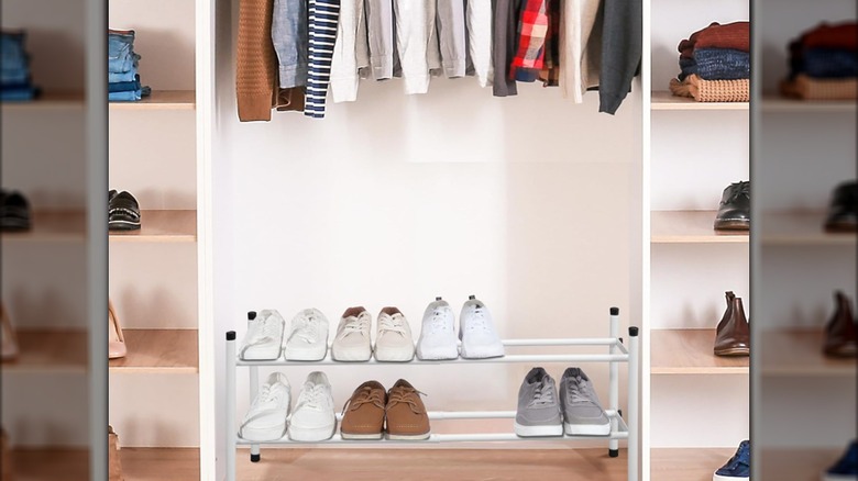 Men's shoes on a white two-tier shoe rack in a closet