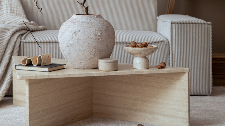 Rough stone bowl and vase with walnuts and tree styled on coffee table