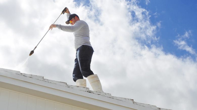 Person pressure-cleaning a roof