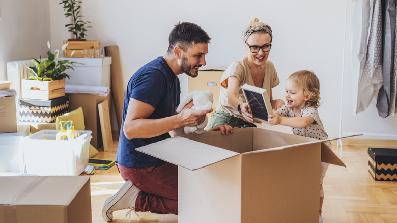 A small family unpacks a box full of their belongings.