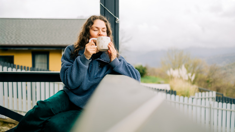 Person holding mug on porch in autumn