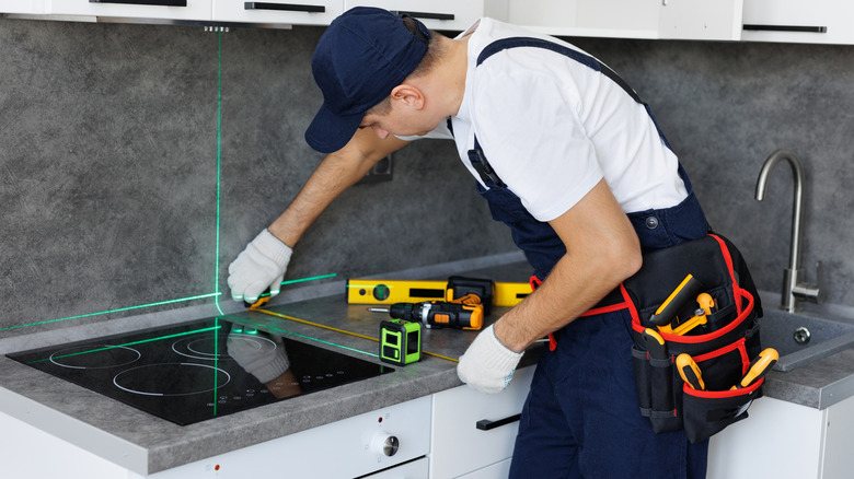 Worker installing stone countertops with laser level