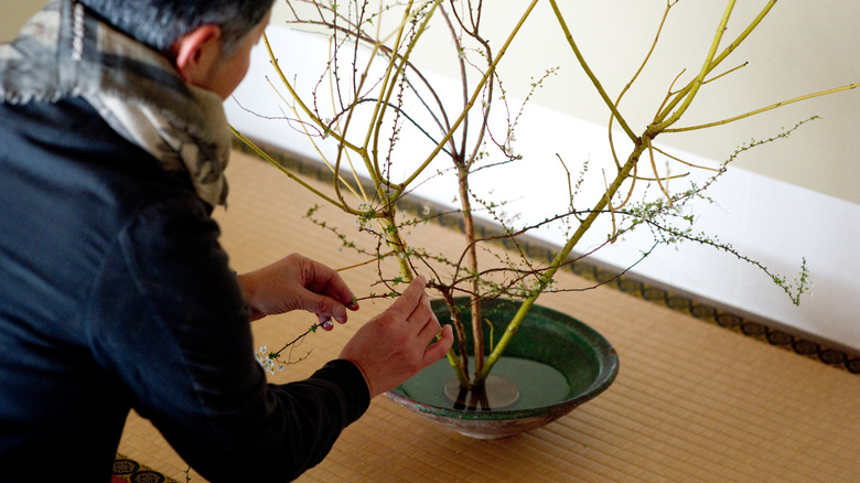 A person using a Kenzan flower frog to make an arrangement