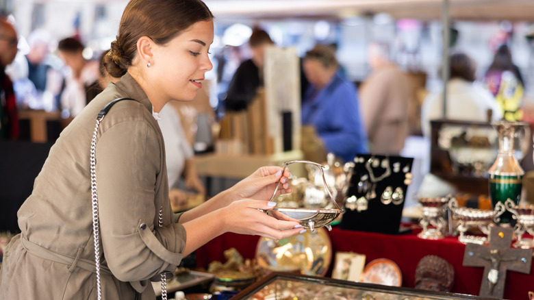 Woman holding up a piece at a thrift shop with several shoppers in the background