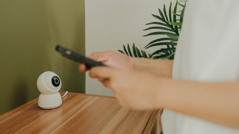 Female hands using smart phone control CCTV at home.