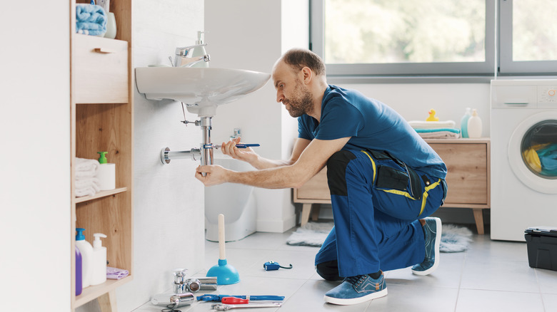A plumber installing a sink in a bathroom.