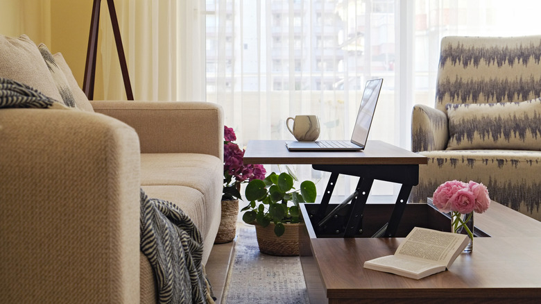 Laptop and mug on a raised top of an adjustable coffee table