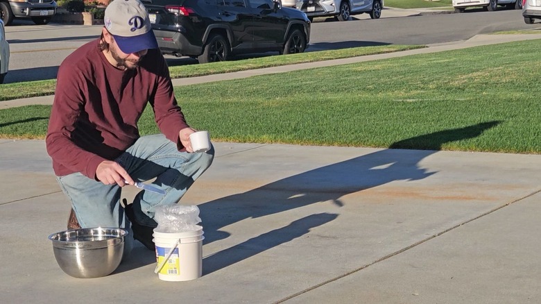 Man inspecting rust stains on a concrete driveway