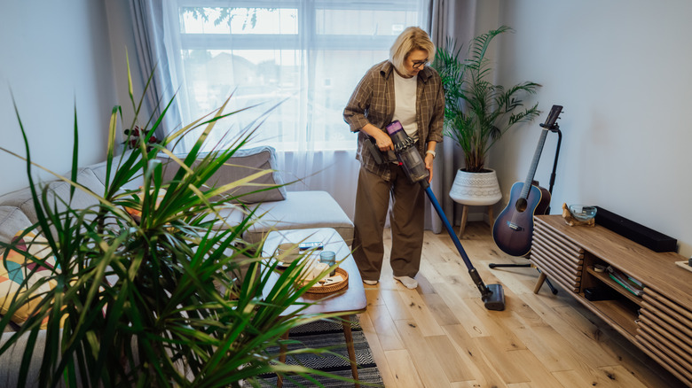 Person vacuuming a room with furniture